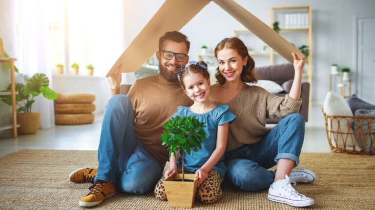 Family holding cardboard roof overhead in living room